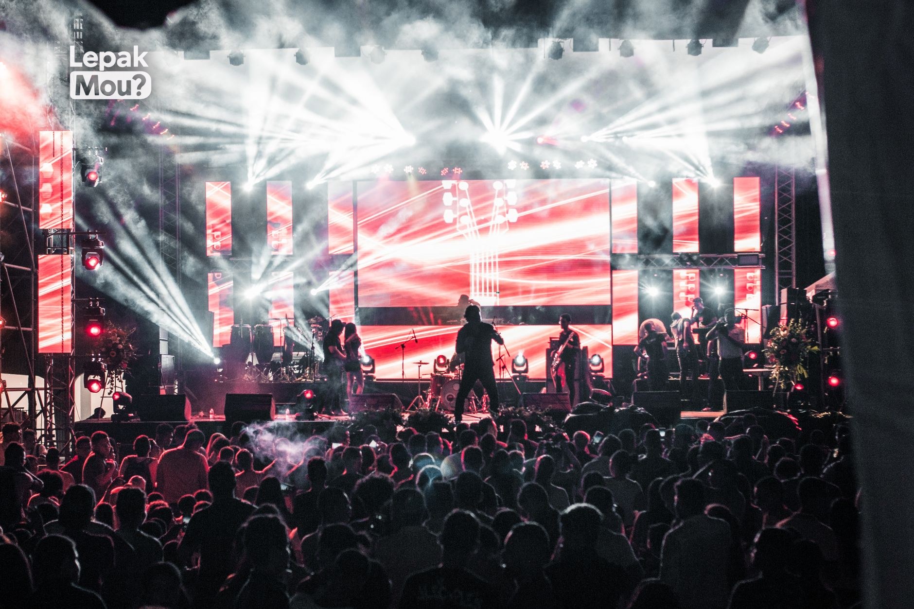 Crowd at a live outdoor concert with stage lights at night